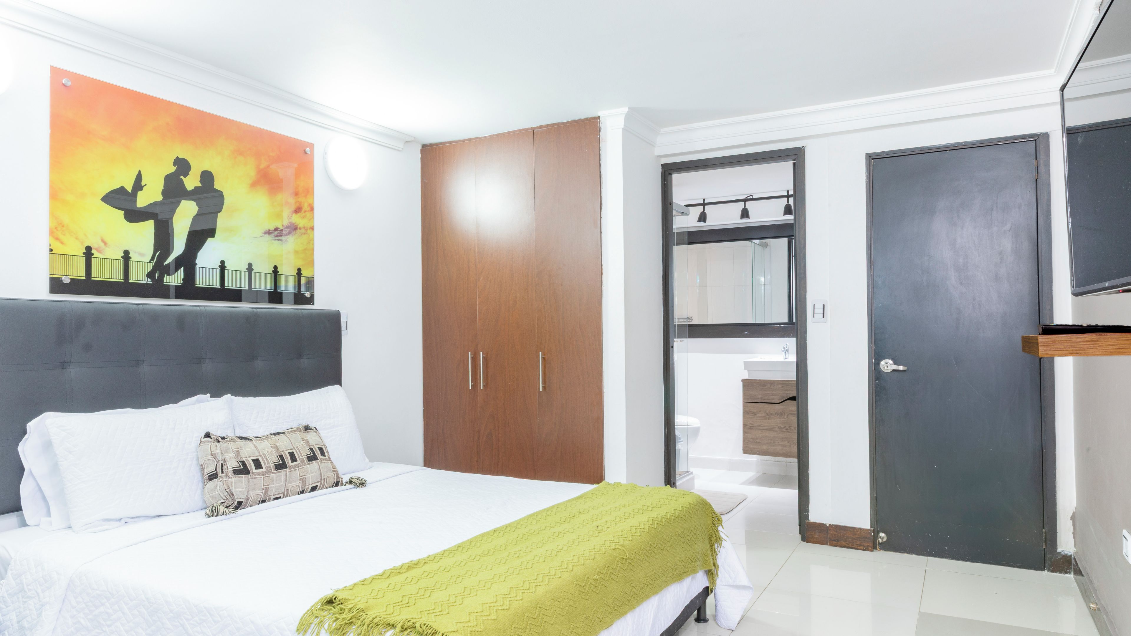 A bedroom with a bed, a wardrobe, a mirror, and a door.