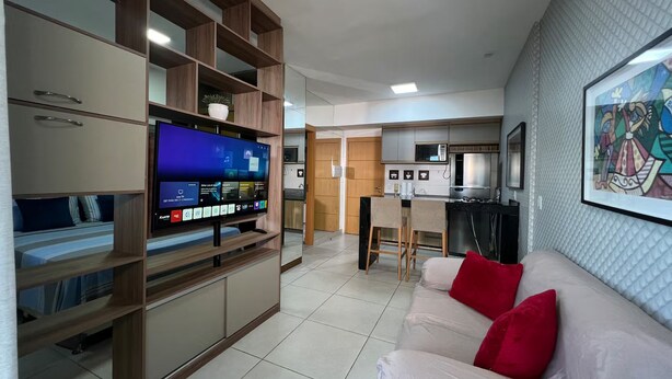 A modern living room with a flat-screen TV, a sofa with red cushions, and a kitchen area in the background. - 1204 Unique · Loft Studio Unique with garage 1204 (Sacramenta)