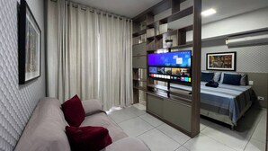 A modern living room with a sofa, a flat-screen TV, a bed, and a large window with curtains. - 1204 Unique · Loft Studio Unique with garage 1204 (Sacramenta)