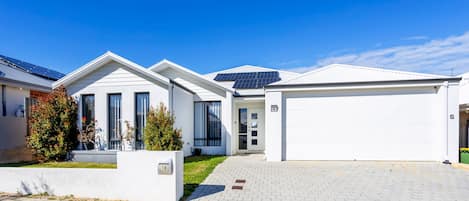 A modern two-story house with a garage, solar panels, and a well-maintained front yard.
