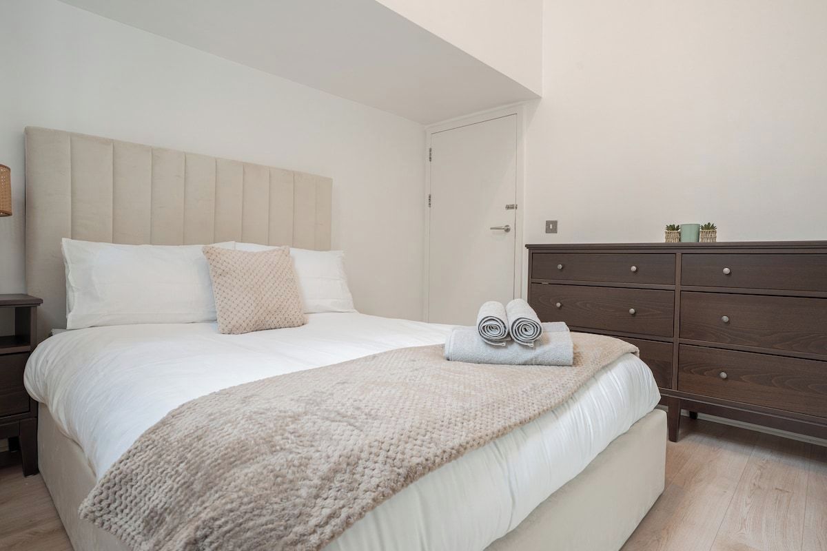 A bedroom with a bed, a nightstand, a dresser, and a door.
