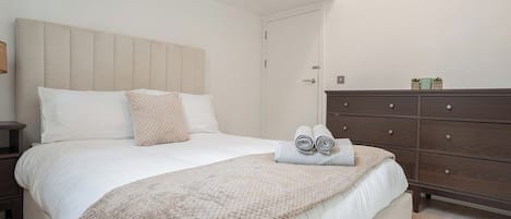 Un dormitorio con cama, mesita de noche, cómoda y puerta.