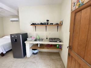 Eine kleine Küchenzeile mit Kühlschrank, Spüle und Gasherd.