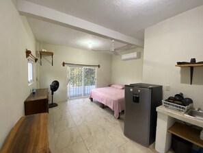 Ein gemütliches Zimmer mit Bett, einer kleinen Küchenzeile, einem Deckenventilator und einem Fenster mit Blick.