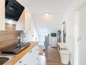 A modern kitchen with a built-in microwave, a coffee maker, and a trash can. - Missi Holiday Apartment (Heringsdorf)
