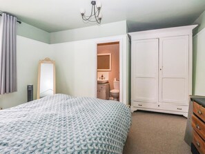 A bedroom with a bed, a wardrobe, a mirror, and a bathroom visible through an open door. - Bowdery (Harrogate)