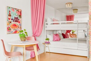 A room with a bunk bed, a dining table with chairs, a small side table, and a potted plant. - Glam Society Music Row-IG Worthy-Outdoor Lounge (Nashville)