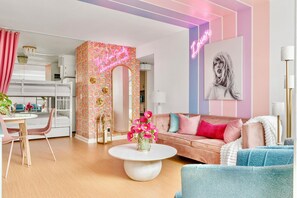 A modern living room with a pink sofa, a round coffee table, and a vibrant floral wallpaper. - Glam Society Music Row-IG Worthy-Outdoor Lounge (Nashville)