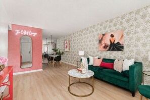 Un salon avec un canapé vert, une table basse ronde et un coin repas comprenant une table et des chaises.