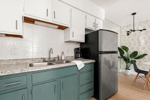 A modern kitchen with white cabinets, a black refrigerator, a granite countertop, and a coffee maker. - The Velvet Lounge Nashville On Music Row-IG Worthy (Nashville)