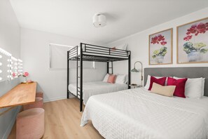 Une chambre avec un lit superposé, une coiffeuse, un bureau et une table de chevet.