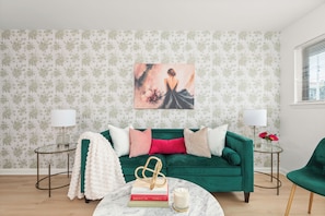 A living room with a green sofa, a white fluffy throw, a glass coffee table with books and a candle, and a painting on the wall. - The Velvet Lounge Nashville On Music Row-IG Worthy (Nashville)