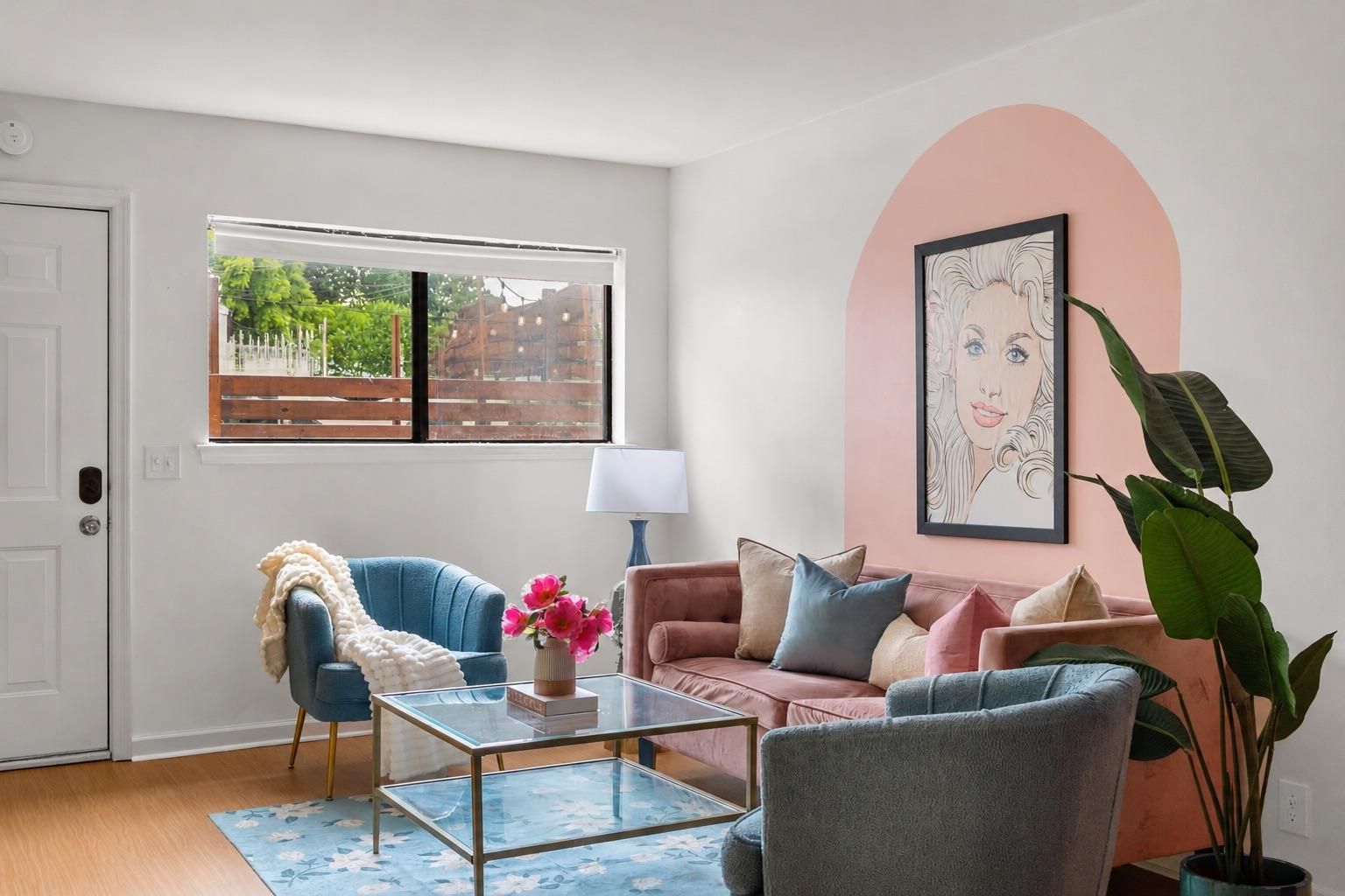 A living room with a glass coffee table, two sofas, a lamp, and a large plant.