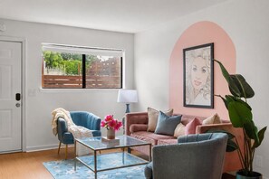 A living room with a glass coffee table, two sofas, a lamp, and a large plant. - Legends Lounge Glam Suite On Music Row IG Worthy (Nashville)