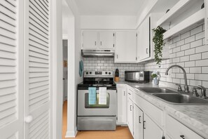 A modern kitchen with white cabinets, a stainless steel oven, a microwave, and a sink. - Legends Lounge Glam Suite On Music Row IG Worthy (Nashville)