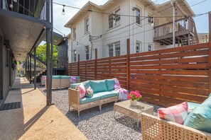 An outdoor seating area with wicker furniture and a wooden fence. - The Muse Girls Glam Suite Near Broadway IG Worthy (Nashville)