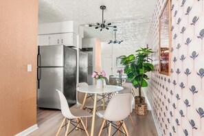 A compact kitchen with modern appliances, a dining area with a round table and chairs, and a decorative plant. - The Muse Girls Glam Suite Near Broadway IG Worthy (Nashville)