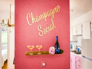 Eine Küche mit roter Wand, einer Kandelaberleuchte und einer Champagnerflasche auf einem Regal.