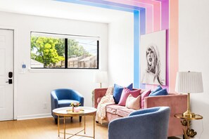 Ein modernes Wohnzimmer mit einem blauen Sessel, einem rosafarbenen Sofa und einem runden Couchtisch.