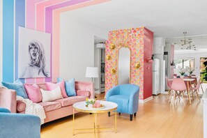 Ein modernes Wohnzimmer mit einem rosafarbenen Sofa, einem blauen Sessel und einem runden Couchtisch.