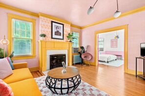 A room with a yellow sofa, a round table, a fireplace, and a bed in the adjacent room. - Taylor's Historic Mansion off Music Row IG Worthy (Nashville)