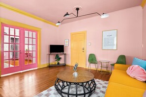 A living room with a round table, a sofa, a television, and a door. - Taylor's Historic Mansion off Music Row IG Worthy (Nashville)