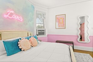 A bedroom with a bed, pillows, a neon sign, a window, and a framed poster. - Historic Dolly + Taylor Suites, Block to Music Row (Nashville)
