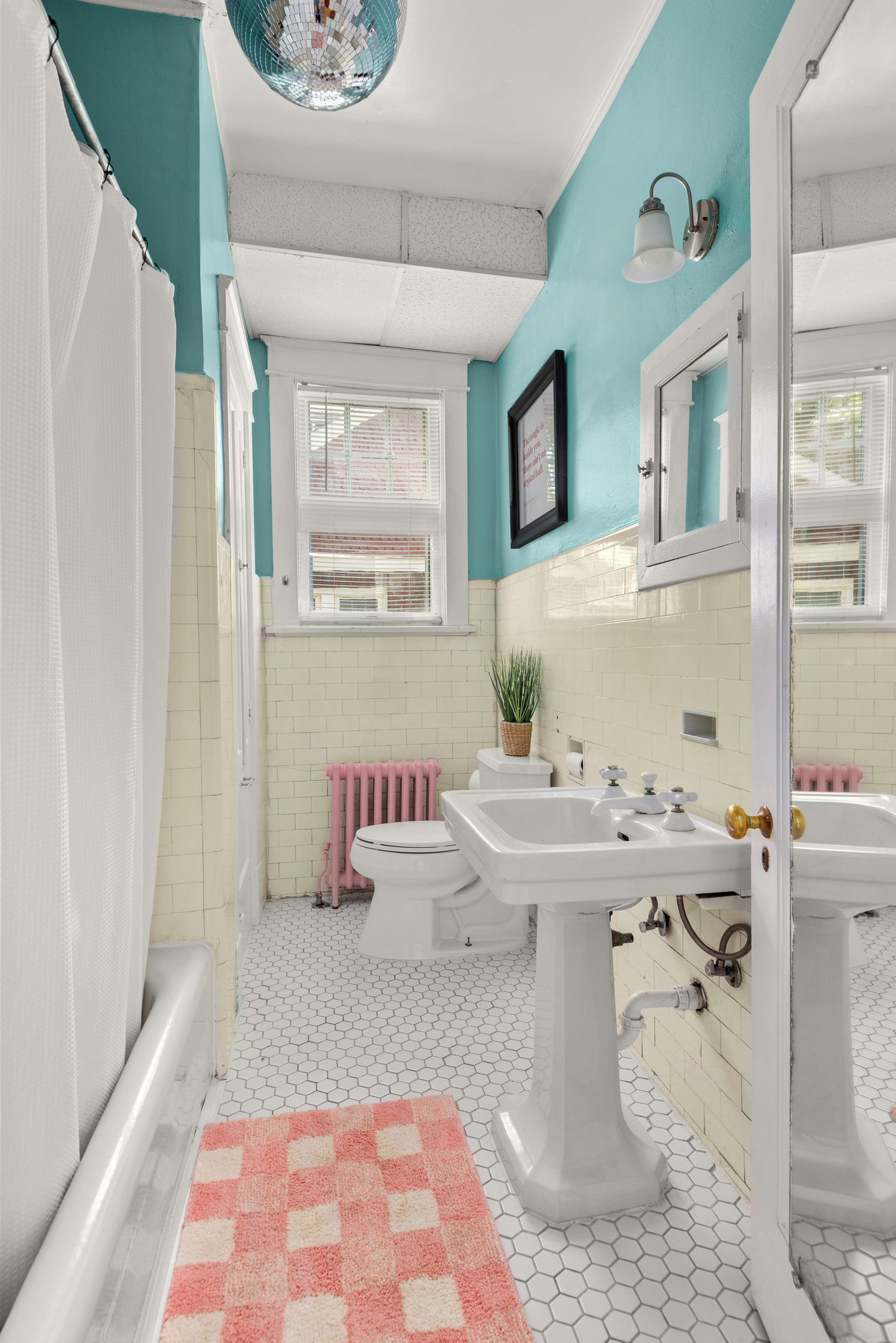Een badkamer met witte en teal muren, een wit wastafel, toilet en een bad.