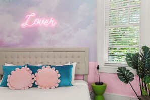 A bedroom with a tufted headboard, a neon sign, and a window with blinds. - Historic Mansion-Sleeps 24-off Music Row-IG Worthy (Nashville)