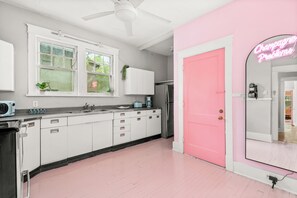 A modern kitchen with white cabinets, a pink door, and a neon sign. - Historic Mansion-Sleeps 24-off Music Row-IG Worthy (Nashville)