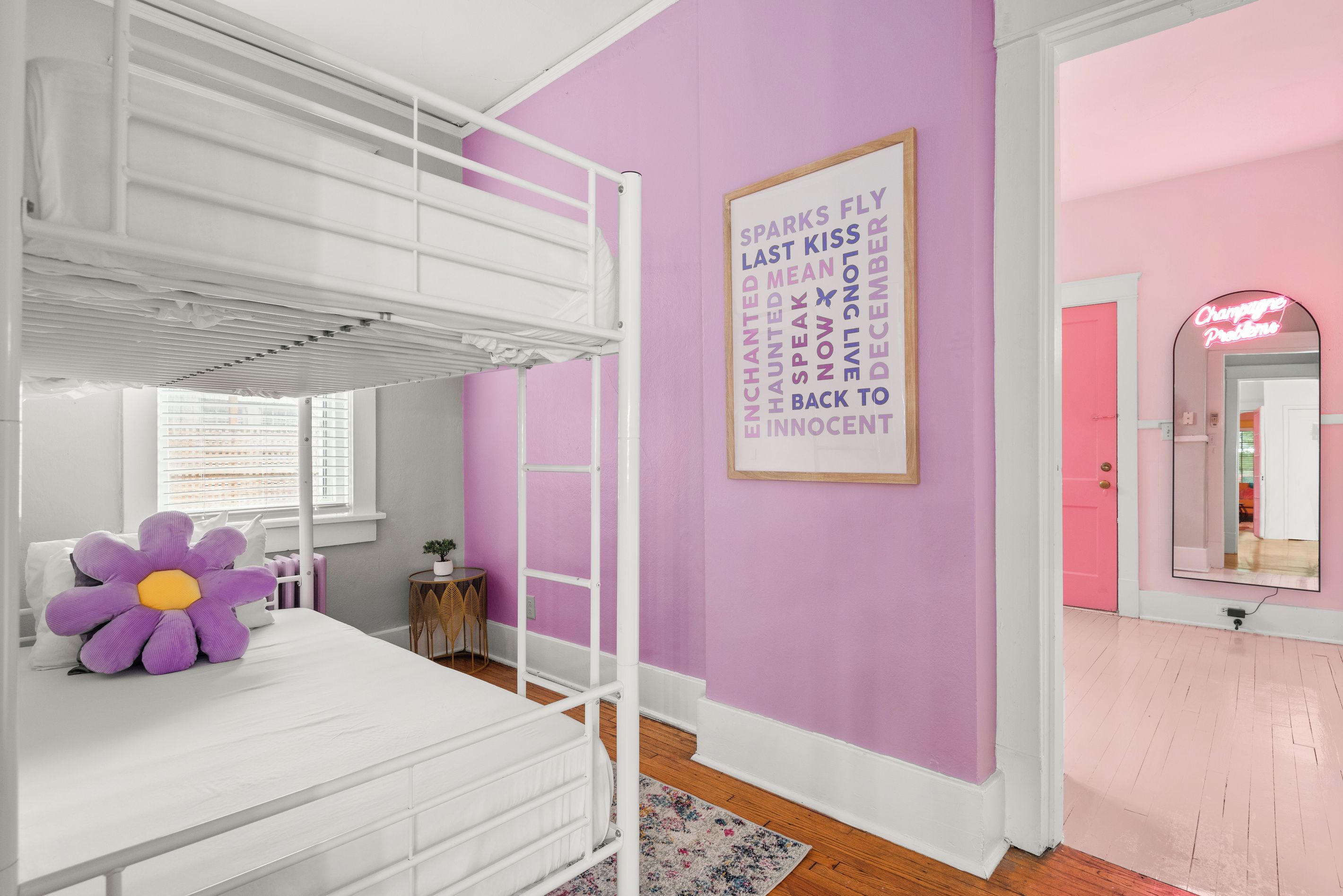 Une chambre avec un lit superposé, un mur violet, un néon et un miroir.