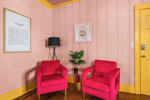 A room with two red chairs, a small table with a lamp, a framed picture, and a yellow door. - Historic Mansion-Sleeps 24-off Music Row-IG Worthy (Nashville)