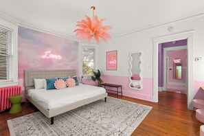 Ein Schlafzimmer mit einem Bett, einer pinkfarbenen Deckenleuchte und einem Neonlicht an der Wand.