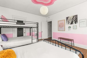 A bunk bed room with a bunk bed, a single bed, a hanging light fixture, and a wall with framed pictures. - Historic Mansion Dolly Glam Near Broadway IGWorthy (Nashville)