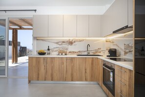 Eine moderne Küche mit Holzausstattung, einer Marmor-Spritzschutzleiste und einem Einbauofen.