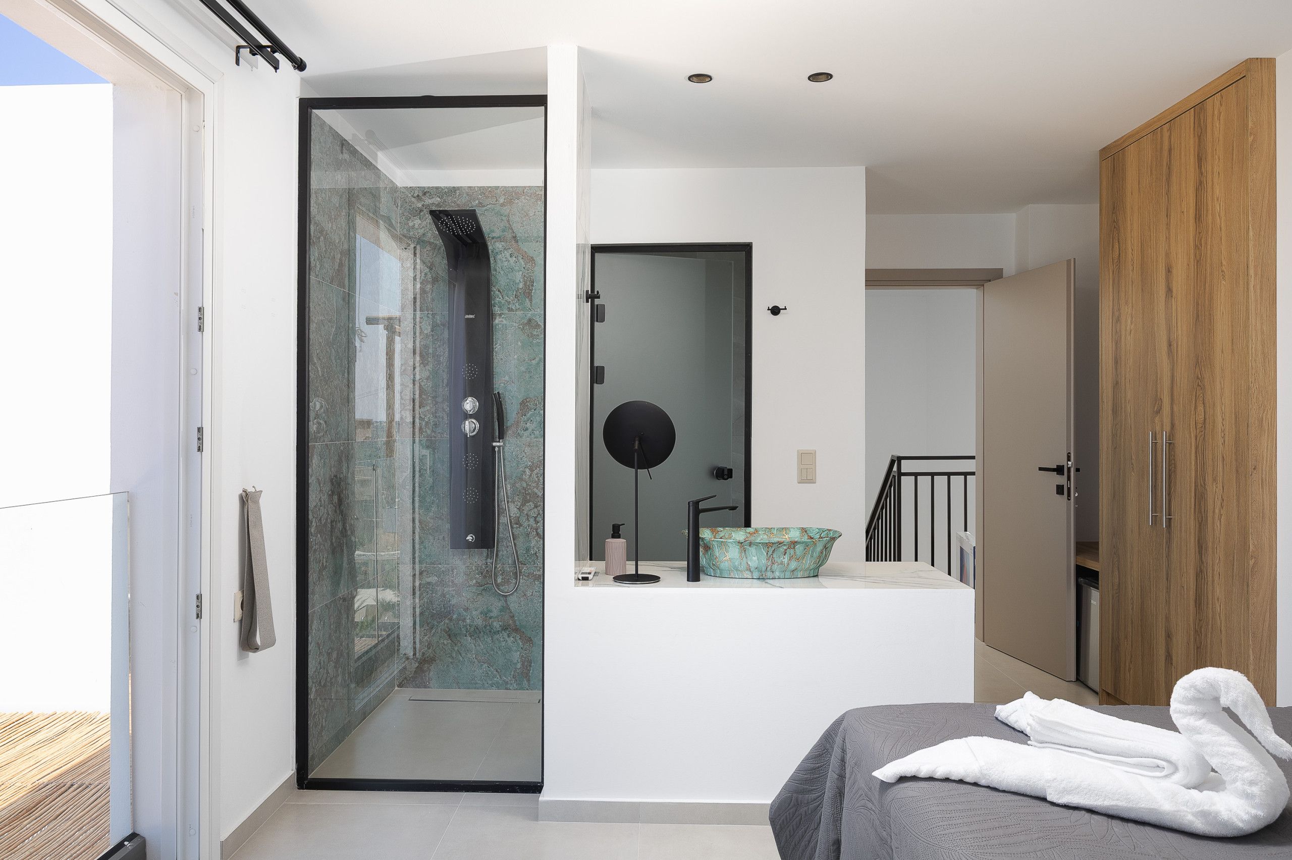A modern bathroom with a glass shower enclosure, a freestanding sink, and a wooden wardrobe.