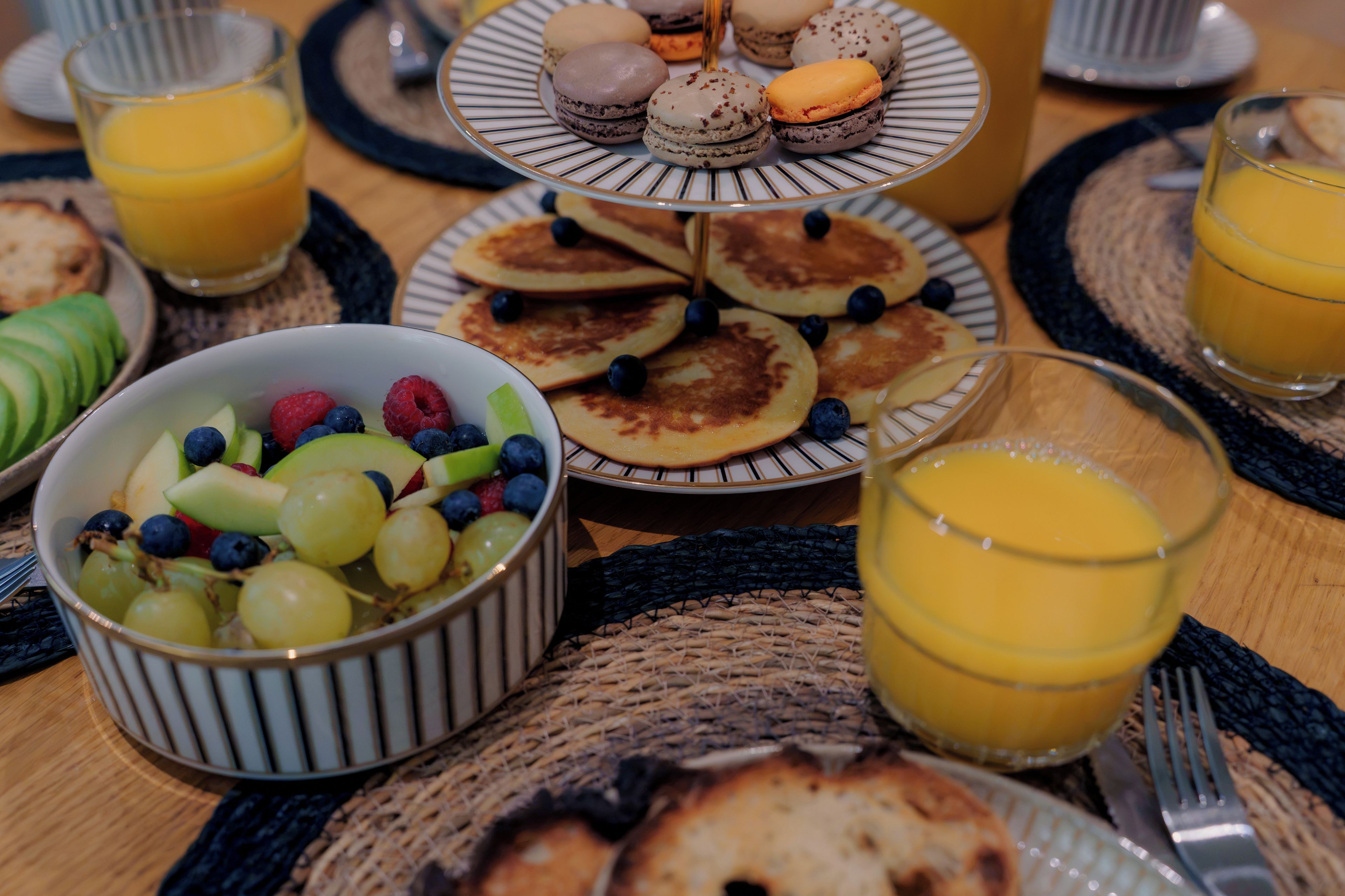 Desayuno con tortitas, un bol de fruta y zumo de naranja.