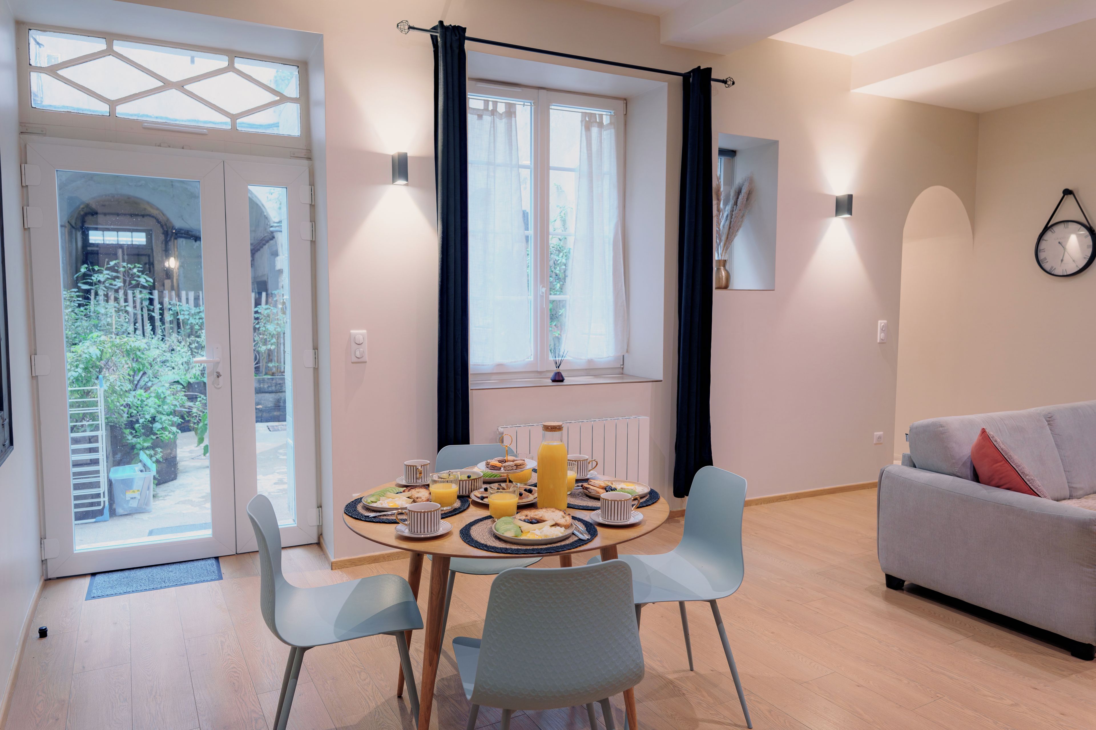 Zona pranzo con tavolo apparecchiato per la colazione, un divano e vista sull'esterno.