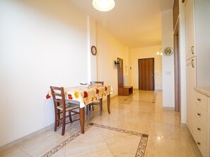 A dining area with a table and chairs, a clock on the wall, and a door leading to another room. - Panoramic Sea-view Apartment (Trecastagni)