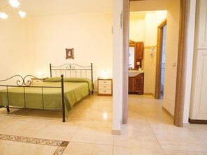 A bedroom with a bed, bedside table, and a bathroom visible through an open door. - Panoramic Sea-view Apartment (Trecastagni)