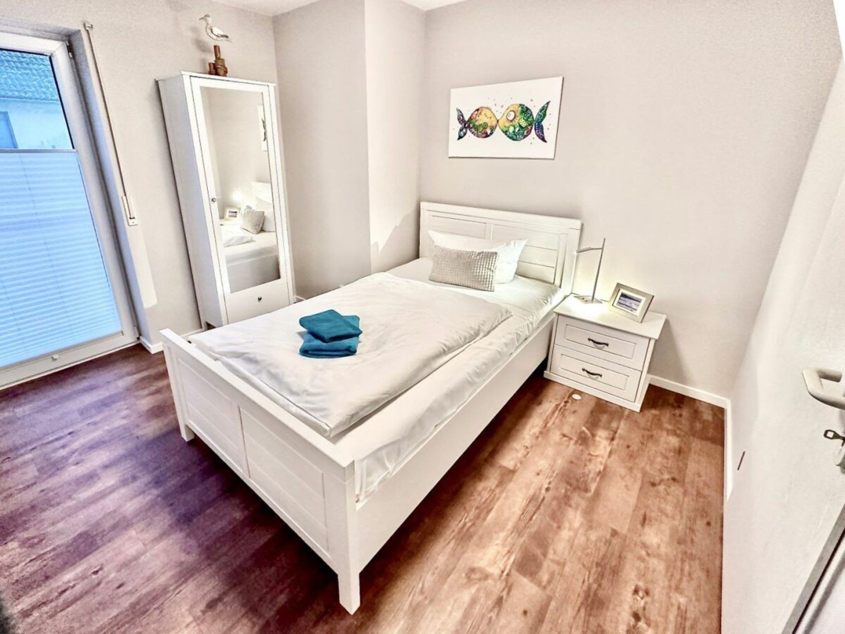 A bedroom with a bed, a nightstand, a dresser, and a painting on the wall.
