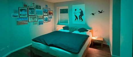 A bedroom with a bed, wall art, and a ceiling light.
