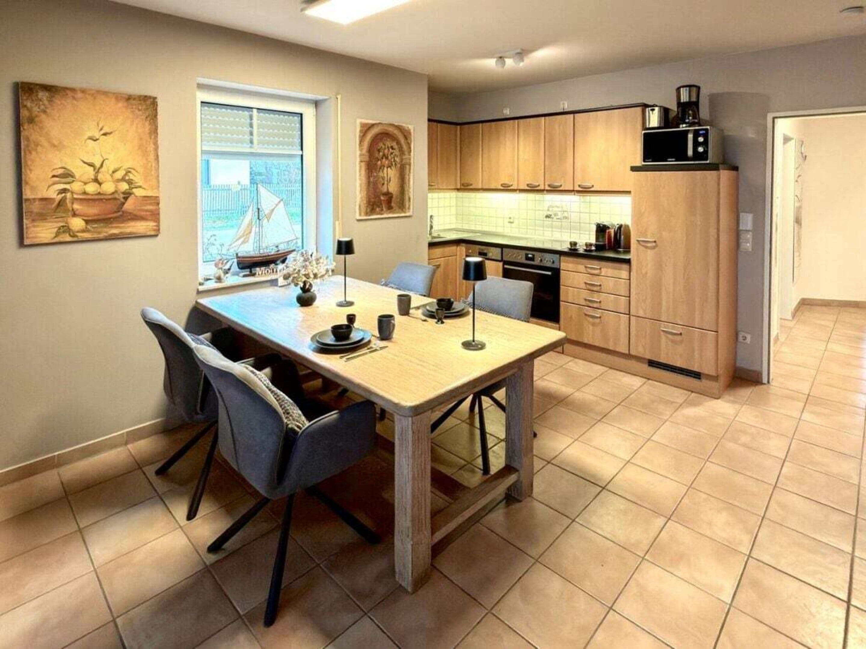A modern kitchen with wooden cabinets, a dining table with chairs, and a window with blinds.