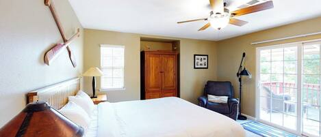 A bedroom with a bed, a ceiling fan, a wooden wardrobe, a chair, and a window.