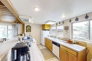 A kitchen with a stove, refrigerator, and wooden cabinets. - The Lakefront Retreat (Bass Lake)