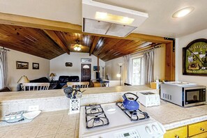 A kitchen with a gas stove, microwave, and a dining area with a table and chairs. - The Lakefront Retreat (Bass Lake)