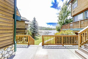 A wooden building with a stone foundation, a wooden deck, and a view of a body of water and trees. - The Lakefront Retreat (Bass Lake)