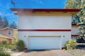 A single-story building with a garage door, surrounded by vegetation and other residential structures. - Creekside & Cozy - Pool, Fireplace & Dog-Friendly (Bass Lake)