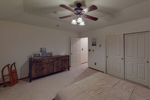 Ein Zimmer mit Deckenventilator, einem hölzernen Schminktisch, einem Bett und einer Tür.