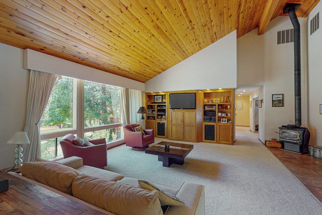 A spacious living area with a high ceiling, a fireplace, and a large window providing a view of the outdoors.